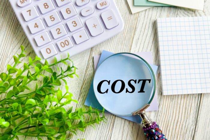 電卓と「COST」の文字を映した虫眼鏡
