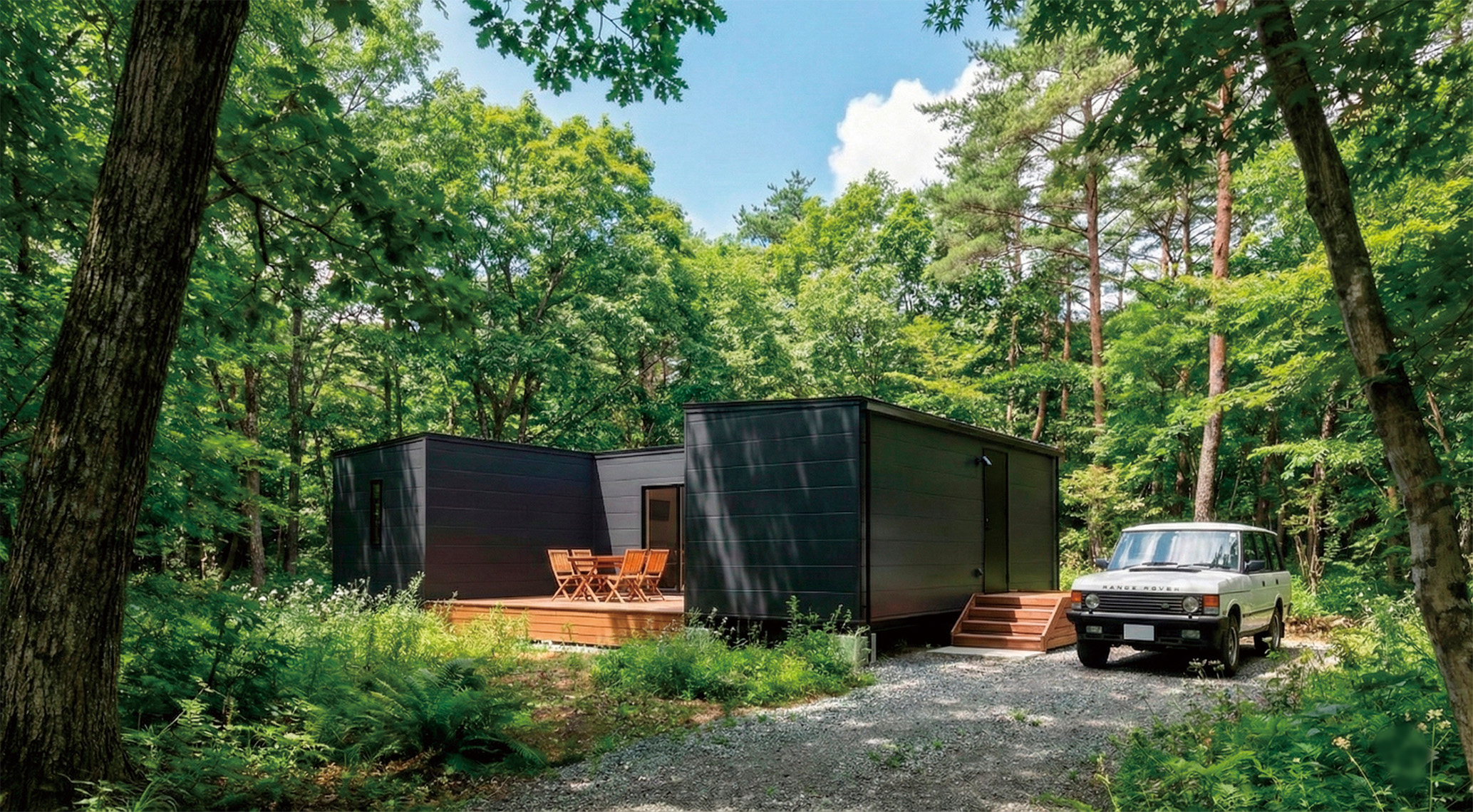 森の中に建つ、2つのユニットをL字に組み合わせた黒い木製コンテナハウスとウッドデッキ