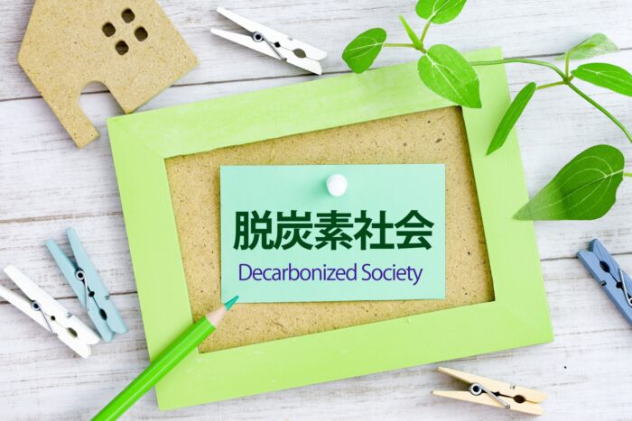 緑のフレームに入った「脱炭素社会 Decarbonized Society」のカードと家のオブジェ