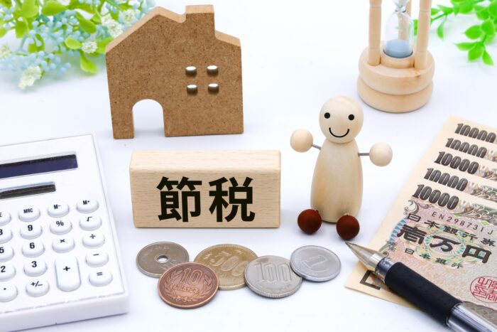 中古アパートのリフォームによる節税と集客力向上を表す「節税」ブロックと電卓・紙幣