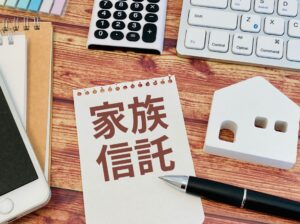 家族信託をイメージしたメモ帳と電卓・家の模型