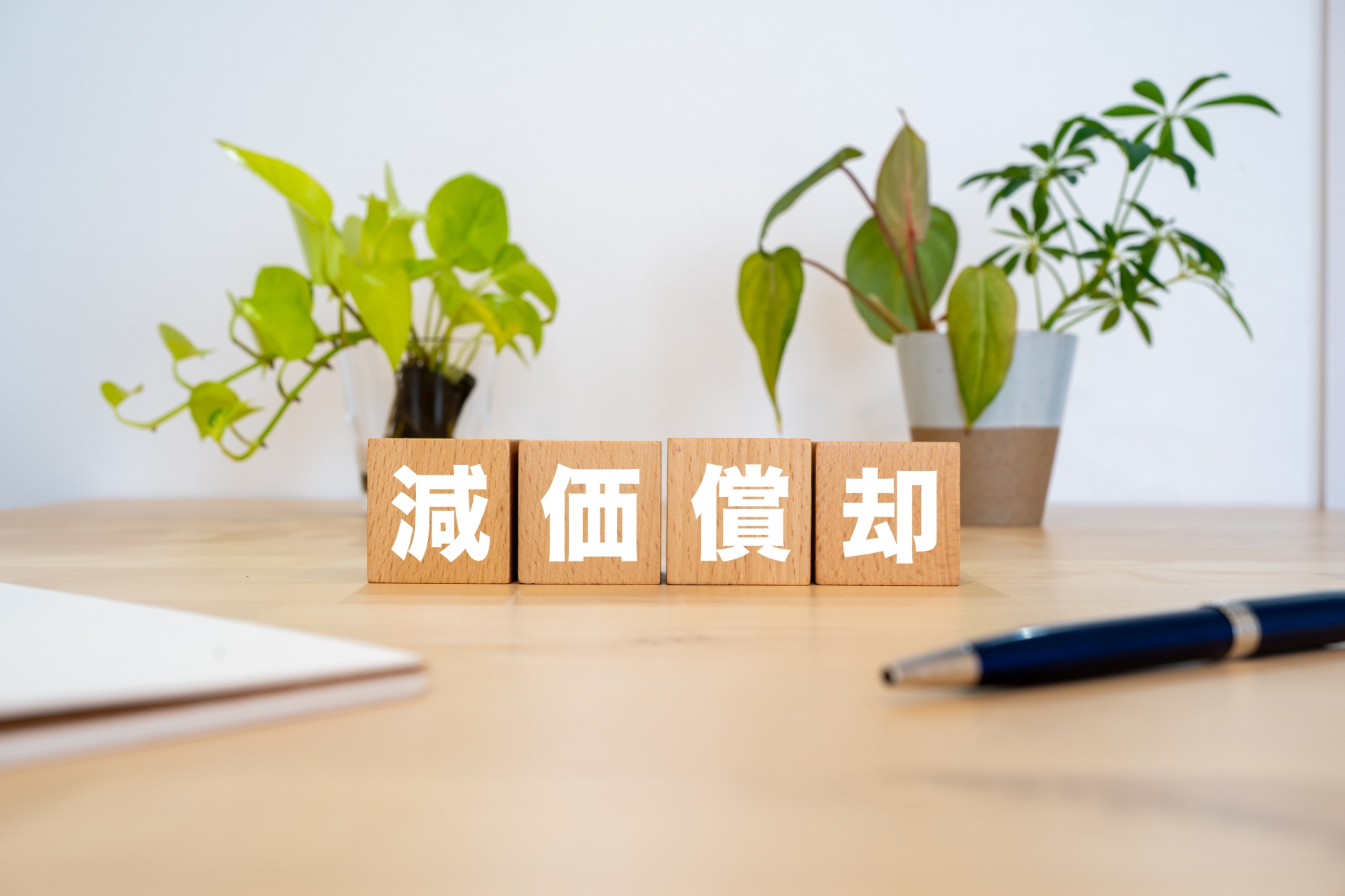 中古アパートの減価償却と節税効果を解説する「減価償却」のブロックとペン